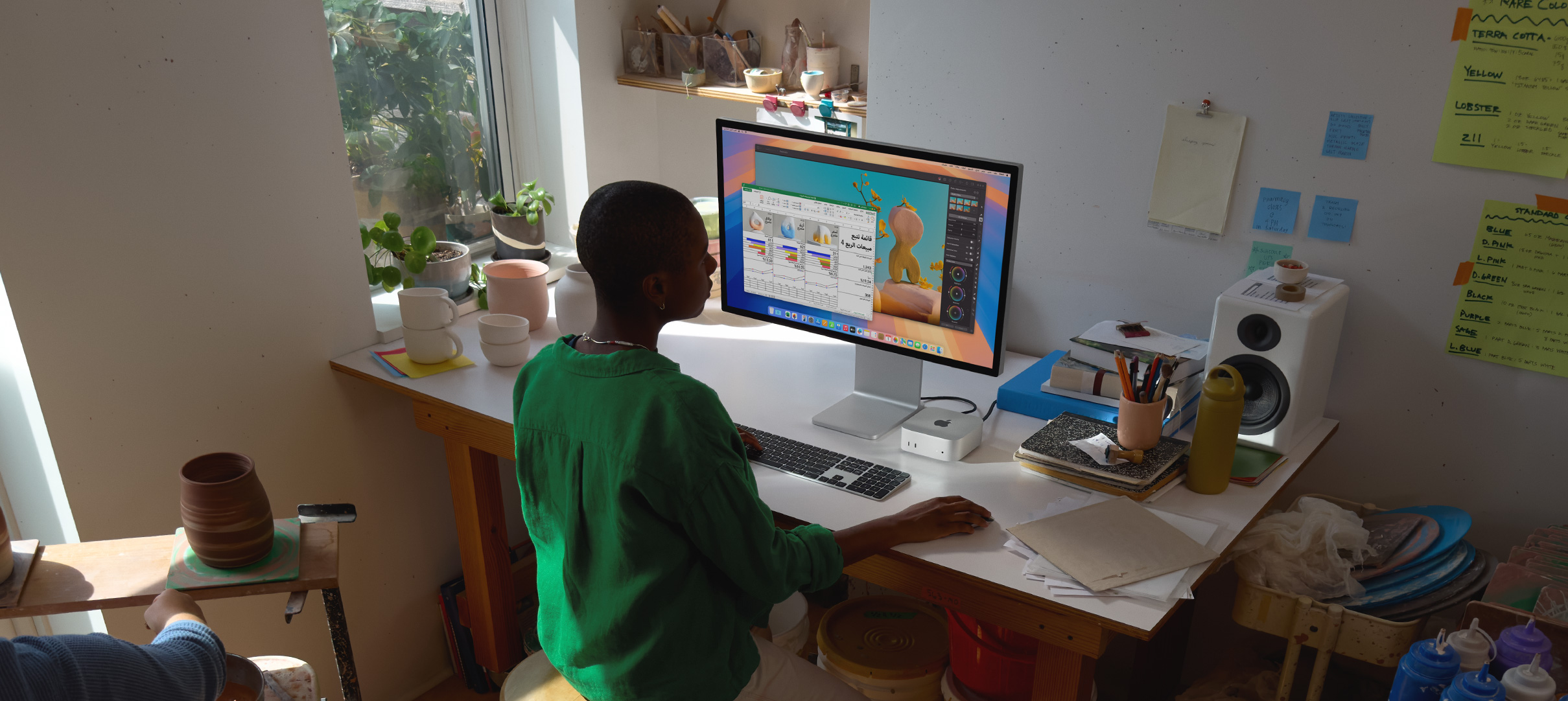 شخص يستخدم جهاز Mac&nbsp;mini على مكتب، ويشاهد شاشة عرض مع نشاط تطبيق ملون