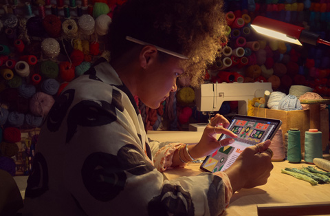 Osoba siedząca przy biurku powiększa obraz na ekranie iPada za pomocą dwóch palców.