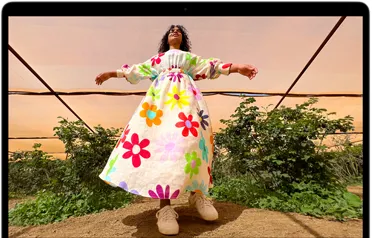 MacBook Air 螢幕顯示一個人穿著鮮艷色彩服裝的照片，展示 Liquid Retina 顯示器的顏色範圍和解析度