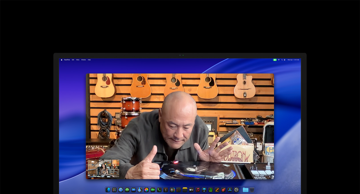 Під час відеовиклику людина в музичному магазині уважно розглядає програвач платівок, залишаючись у центрі кадру завдяки камері Center Stage