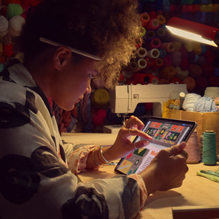 Een persoon die aan een bureau zit en twee vingers op het scherm van een iPad gebruikt om in te zoomen op een afbeelding.