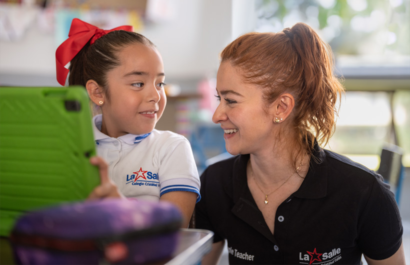 Eleane Ruth Guzmán Padilla shares a moment with a student in the classroom at Colegio Cristóbal Colón.