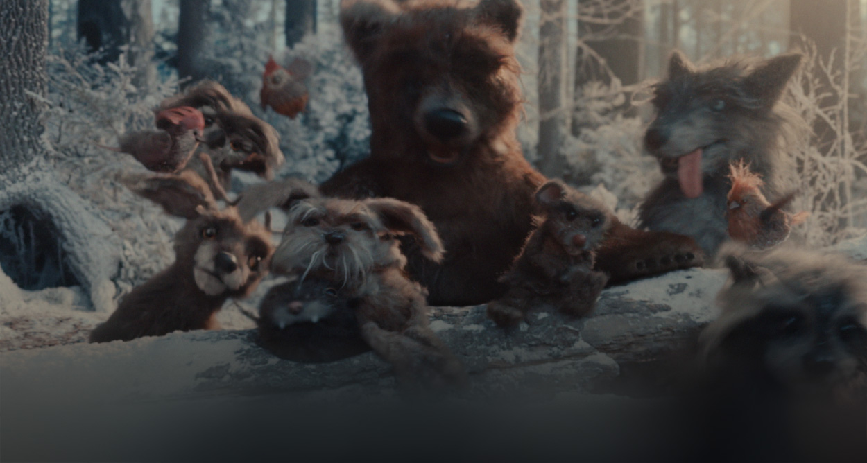 Group of woodland creatures gathered around a log in a snowy forest
