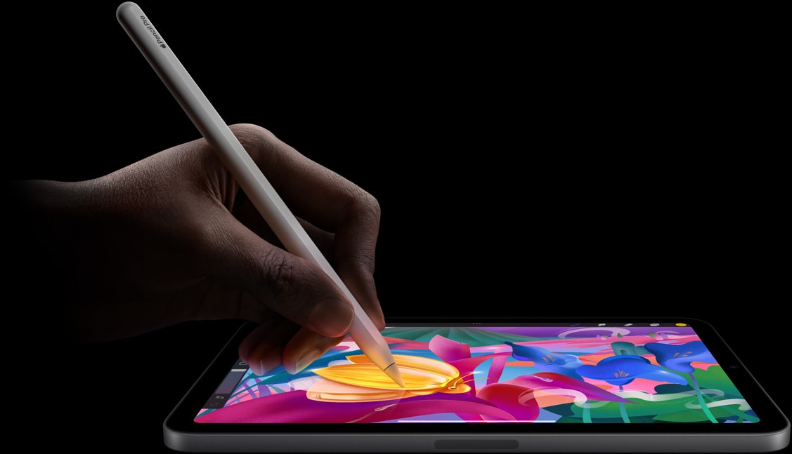 Ruka drží ceruzku Apple Pencil Pro a kreslí pestrofarebný obrázok na iPade mini.