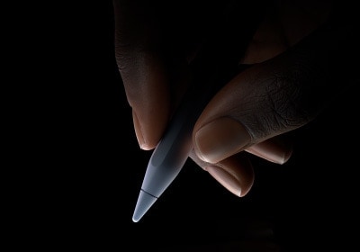 Niekto drží dolnú tretinu ceruzky Apple Pencil Pro medzi palcom a ukazovákom, pripravený na písanie.