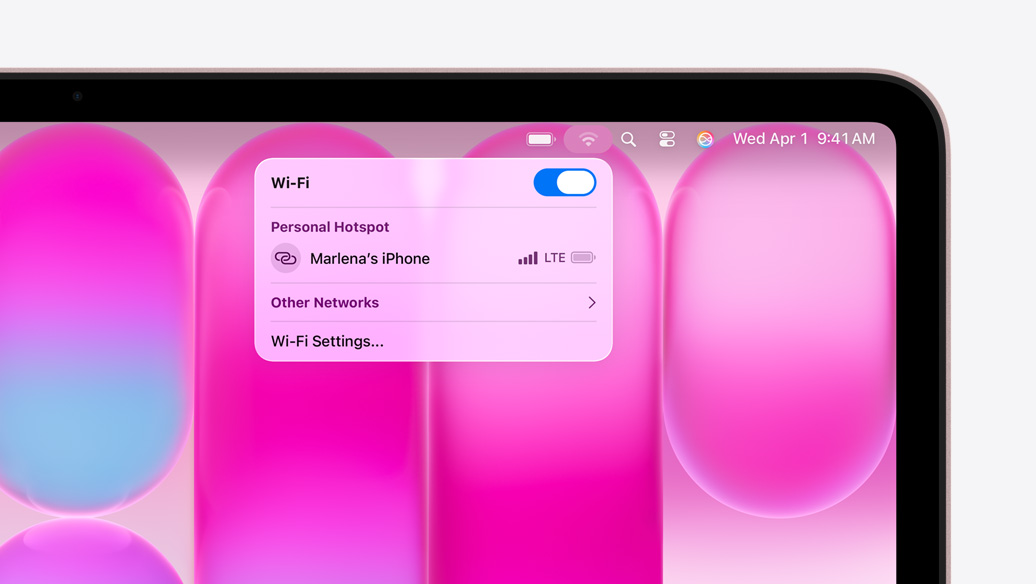 MacBook Neo i fargen svak rosa med en wifi-meny som viser Delt internett-delen med muligheten til å velge «Marlena's iPhone».