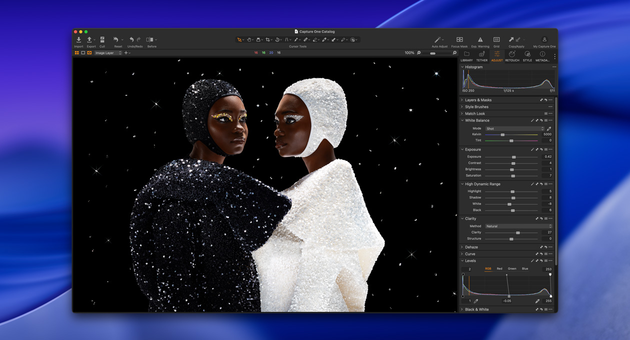 Eine in Schwarz gekleidete Person steht schräg neben einer in Weiss gekleideten Person, um die Helligkeit und den Kontrast des Studio Display XDR zu zeigen
